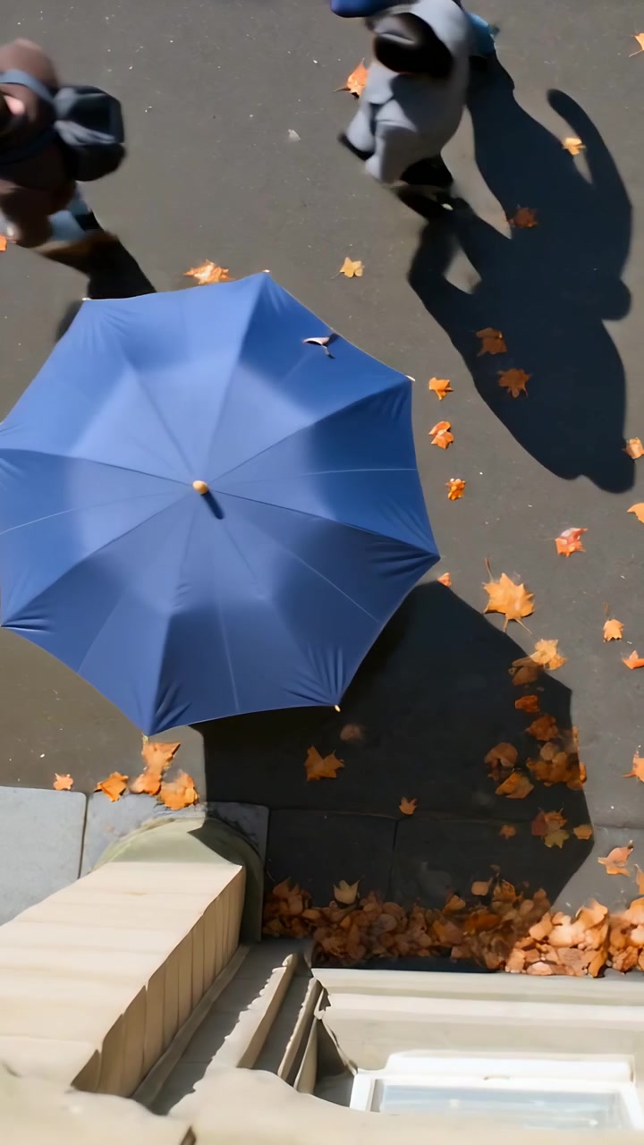 Video verticale: La telecamera effettua una panoramica verso il basso, rivelando una sporgenza sopra il marciapiede, con passanti che camminano accanto a un ombrello blu.