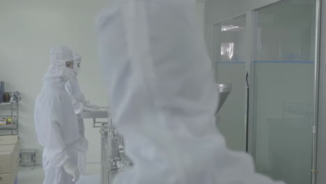 technicians in protective clothing pharmaceutical production line in modern factory, laboratory worker filling vials with liquid, scientist testing medical vials on conveyor belt