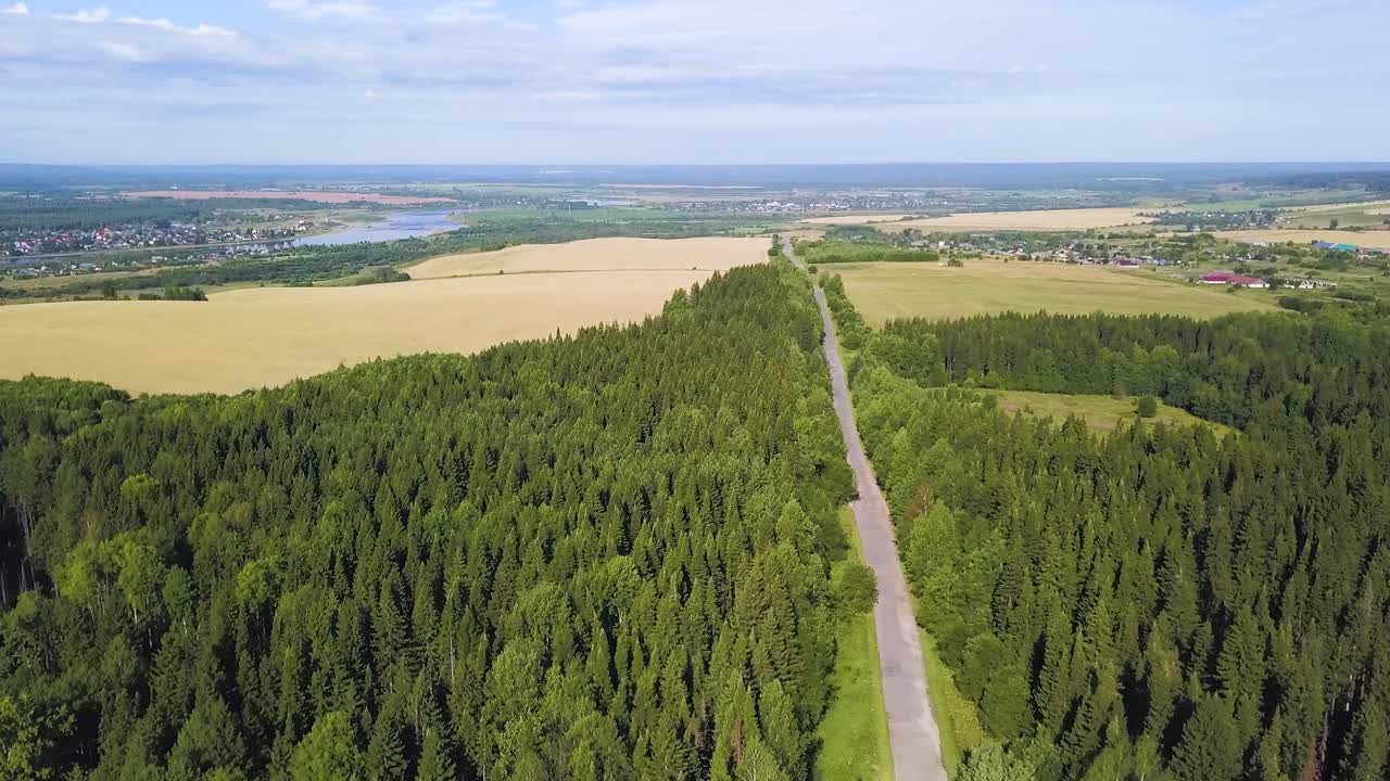 Ilmakuva mutkittelevasta tiestä metsä- ja maaseutumaisemassa