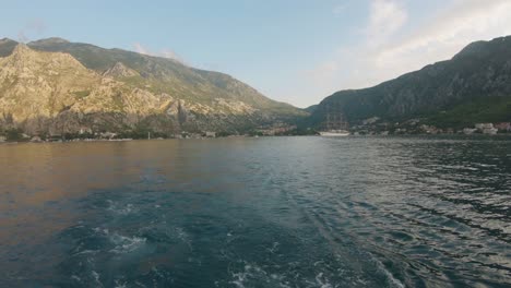 Static-POV-shot,-from-a-boat-leaving-Kotor-city,-surrounded-by-mountains,-there´s-boats-on-the-adriatic-sea,-on-a-sunny-day,-in-Montenegro