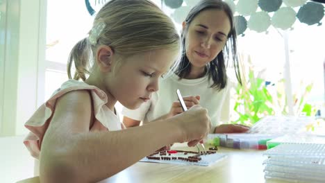 madre y hija haciendo una pieza de arte de mosaico