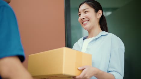 beautiful young woman receiving parcel from blue uniform delivery man f the house with good service from shopping online. courier man delivering a cardboard box postal package to destination.