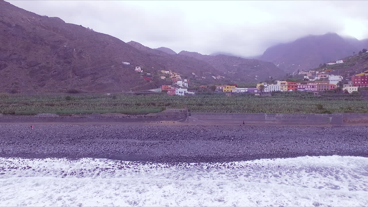 vista aérea de la playa de hermigua, valle, plantación de plátanos, casas coloridas y montañas en el valle de hermigua, al norte de la gomera, islas canarias, españa en un día nublado