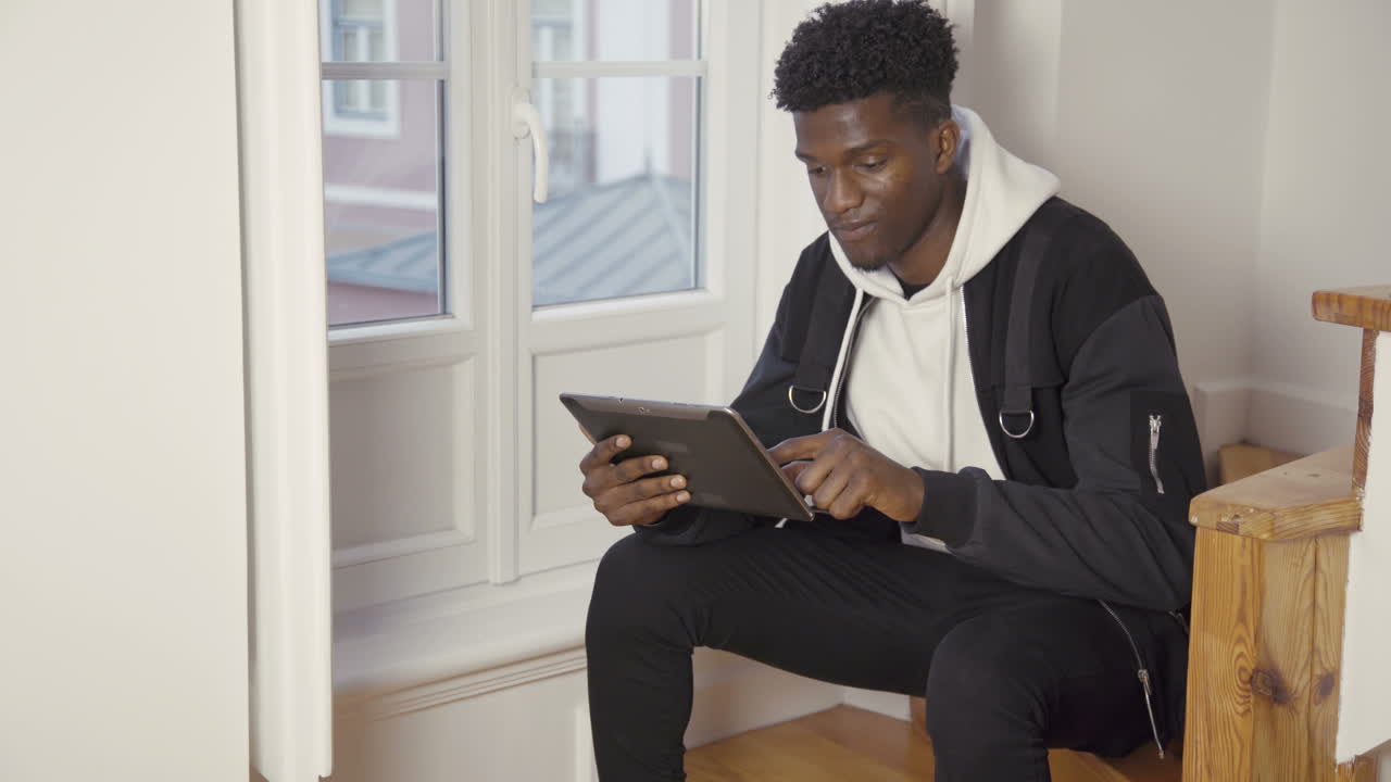 Portrait of serious man sitting at home using digital tablet