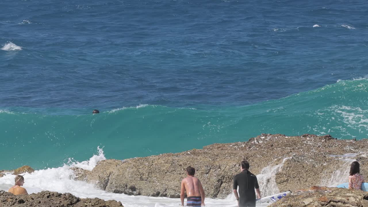 personas disfrutando de las olas en una zona costera rocosa