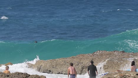 people enjoying waves at a rocky coastal area