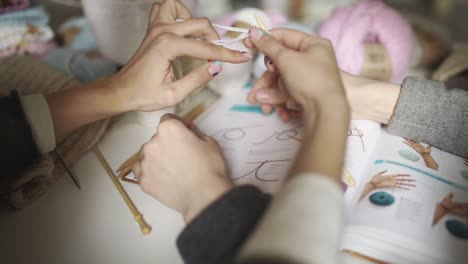 Two-sisters-together-learning-to-knit-looking-in-knitting-pattern.-Knitting-hand