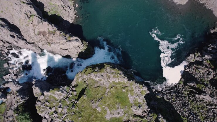 Drone che vola in cerchio con la telecamera inclinata verso il basso sopra una cascata in Islanda 4K