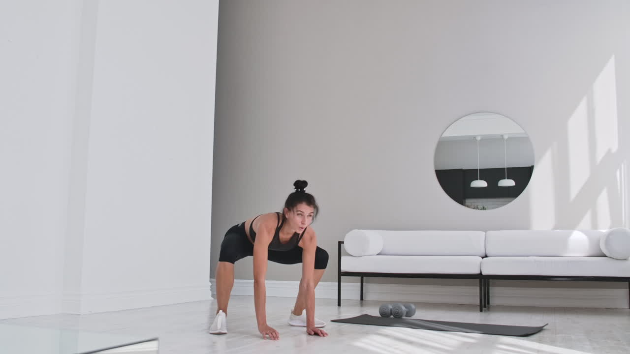 mujer de fitness haciendo ejercicio de burpee en casa. toma media de mujer joven haciendo flexiones y ejercicios de salto en cámara lenta. concepto deportivo