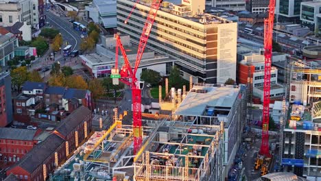 sitio de construcción, grúas rojas y tráfico callejero en sheffield, aéreo