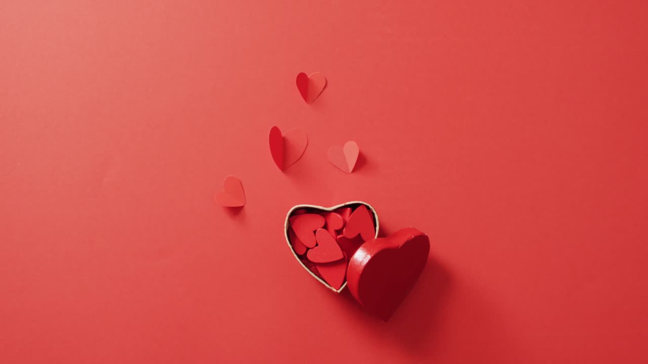 Red paper hearts in box on red background at valentine's day