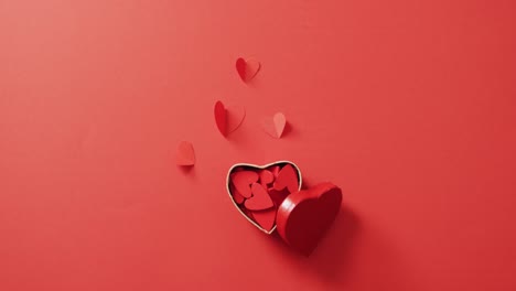 red paper hearts in box on red background at valentine's day