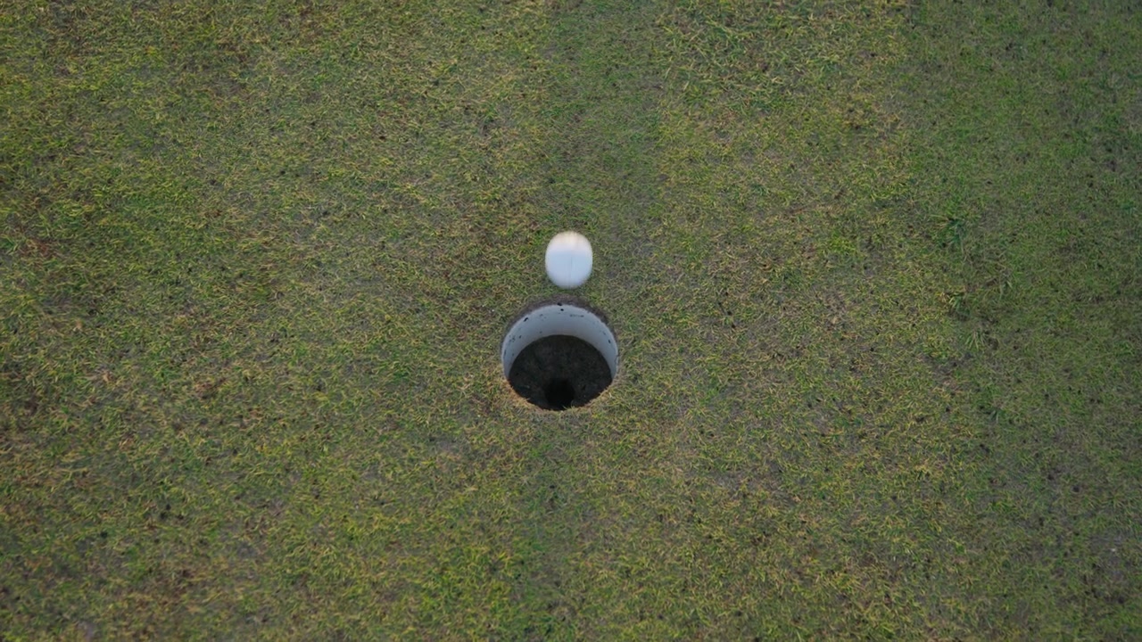 Colpo in rotazione di una pallina da golf imbucata al tramonto