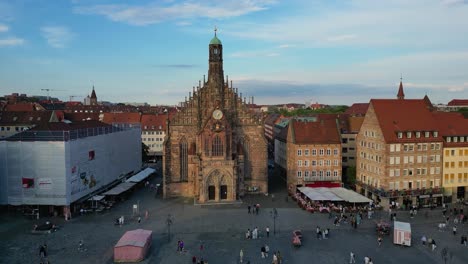 4k aerial drone video of church tower clock and on the hauptmarkt market square in nurnberg, germany - truck left
