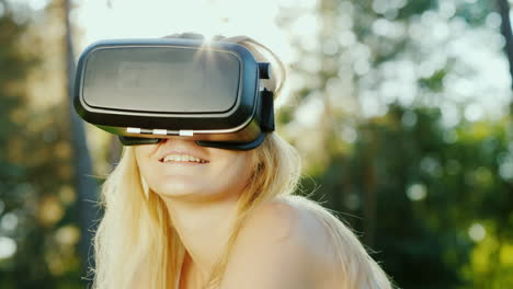 attractive woman in a helmet of virtual reality sits in a beautiful place on the nature slow motion