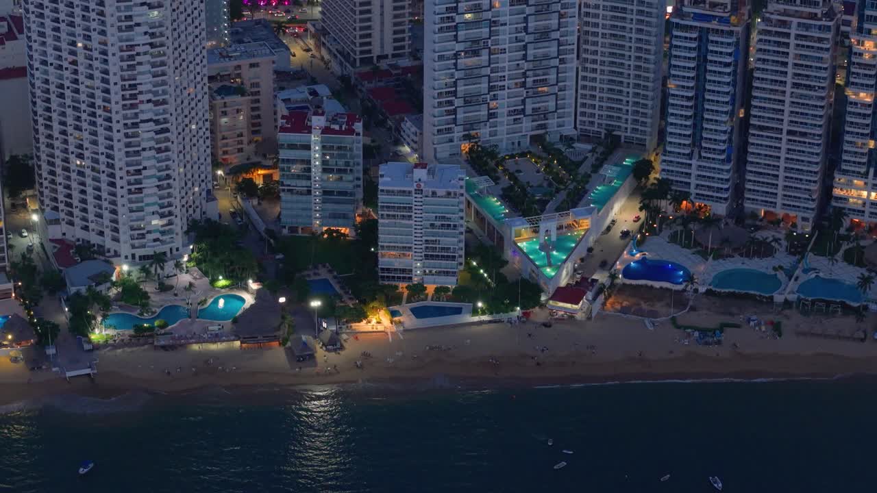 Droneoptagelse af hotelområde med oplyste swimmingpools og rekreative områder om natten