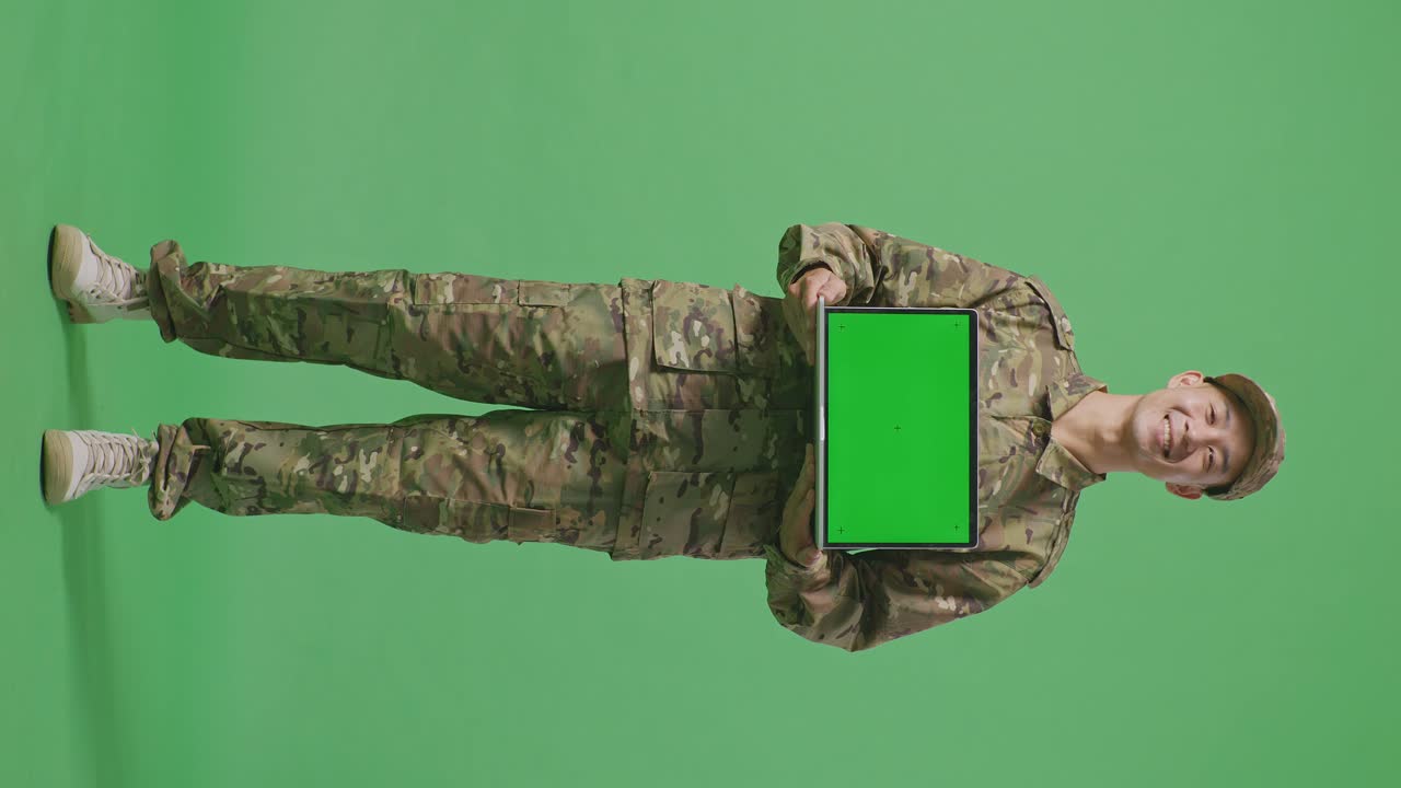 Full Body Of Asian Man Soldier Smiling And Showing Green Screen Laptop To The Camera While Standing In The Green Screen Background Studio