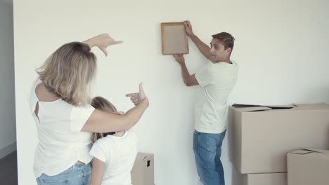 girl with her mom helping dad to choose place for picture