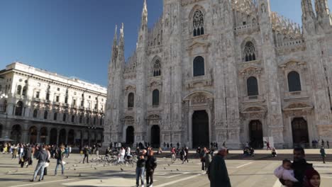 duomo di milano church front and plazza with some people hanging out visiting in milan italy, truck right wide shot