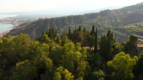 Drone-flies-over-green-hill-to-reveal-small-Italian-village