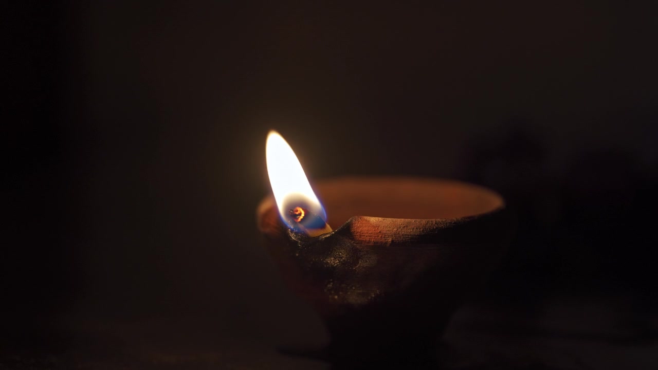 Lampada a olio tradizionale in terracotta accesa nell'oscurità