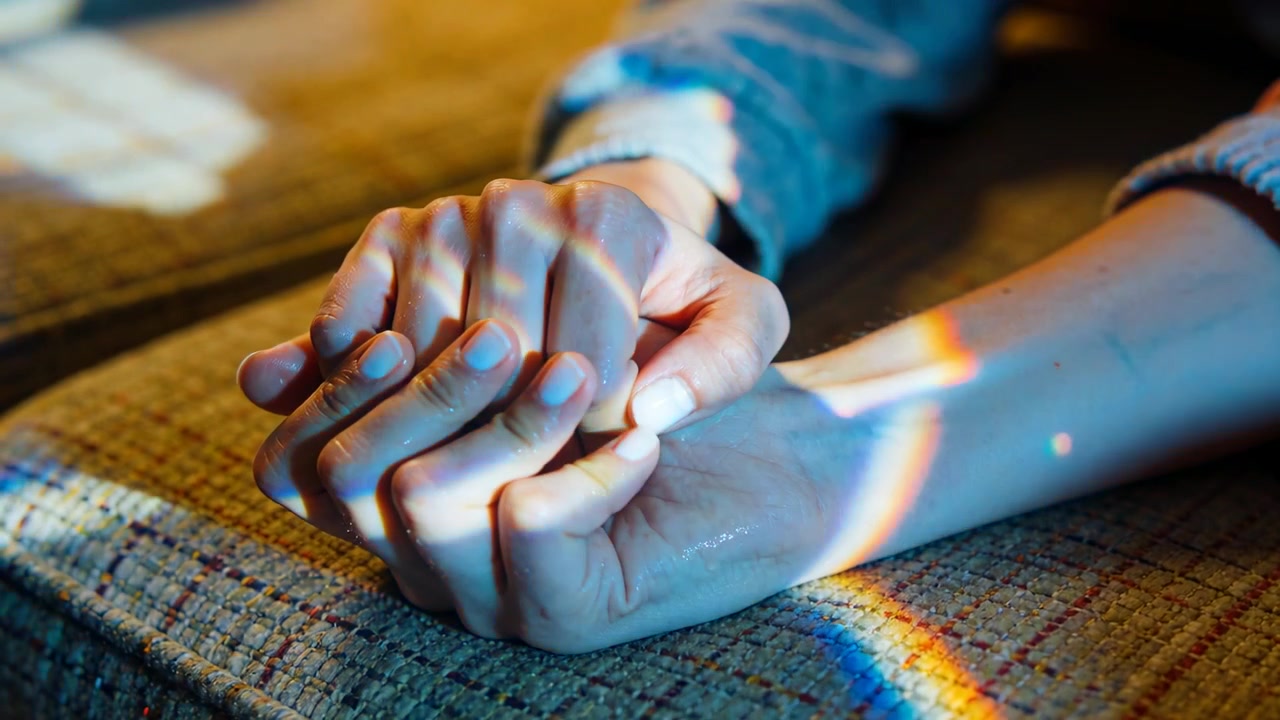 Tomados de la mano en el sofá, la mano que descansa aprieta más para mayor comodidad, con un agarre firme, bajo una luz de arcoíris.