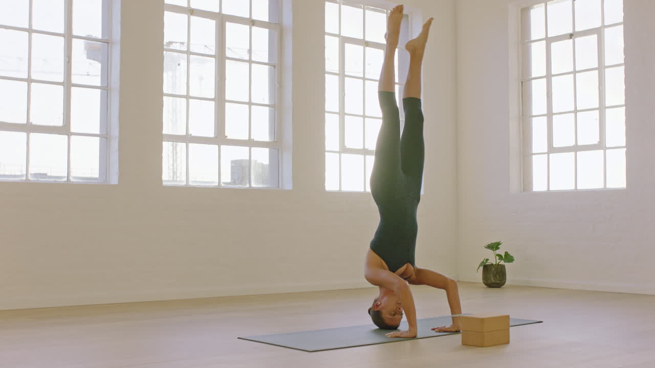 hermosa mujer de yoga practicando postura de parada de cabeza disfrutando de un estilo de vida físico haciendo ejercicio en el estudio estirando el entrenamiento corporal flexible meditación temprano en la mañana en una colchoneta de ejercicios