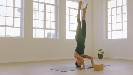 hermosa mujer de yoga practicando postura de parada de cabeza disfrutando de un estilo de vida físico haciendo ejercicio en el estudio estirando el entrenamiento corporal flexible meditación temprano en la mañana en una colchoneta de ejercicios