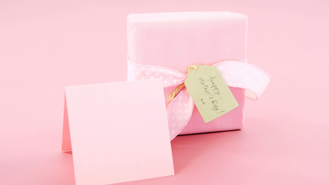 caja de regalos con etiqueta de feliz día de la madre y tarjeta en blanco contra un fondo rosa