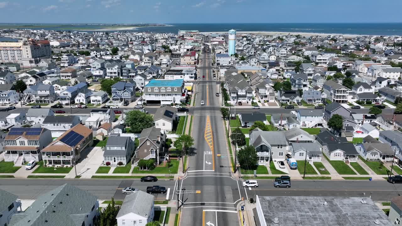 Beach houses in Wildwood with installed solars panels on roof of buildings. Sunny summer day in New Jersey. Traffic on Main Street and junctions. Blue ocean in background. Aerial wide shot