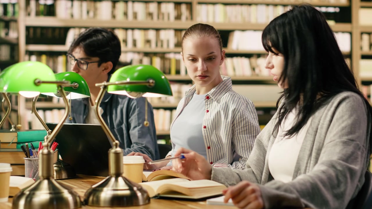 University students discussing with tutor and studying with open books