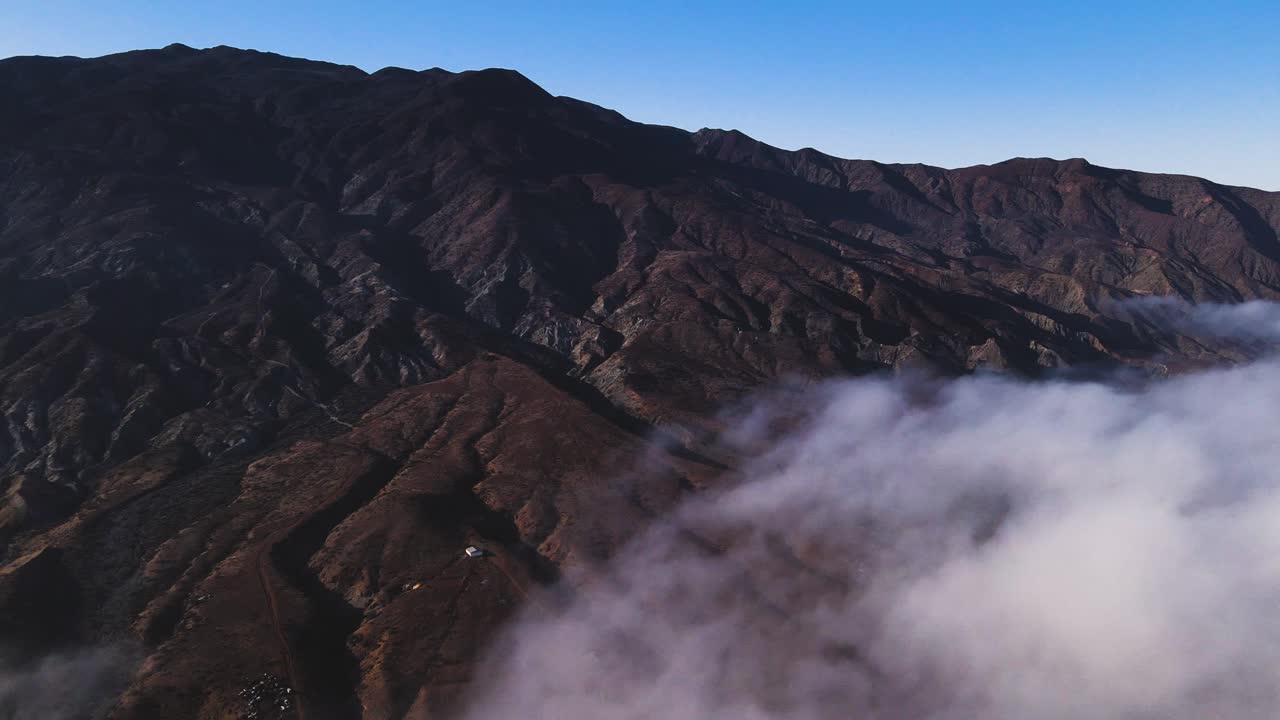 Rugged cliffs along Cedros Island’s coastline with morning mist and soft sunlight illuminating the scene, aerial establishing pan
