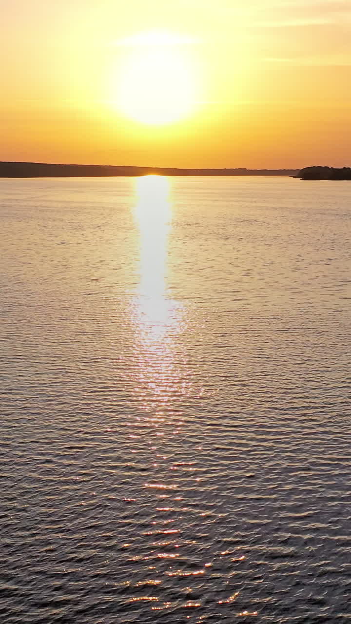 Beautiful sunset is reflecting in the river. Sunset lake landscape. Colorful sky. Vertical video