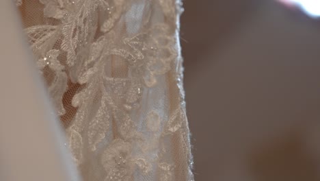 close-up of white lace wedding dress with floral motifs, sequins and soft lighting