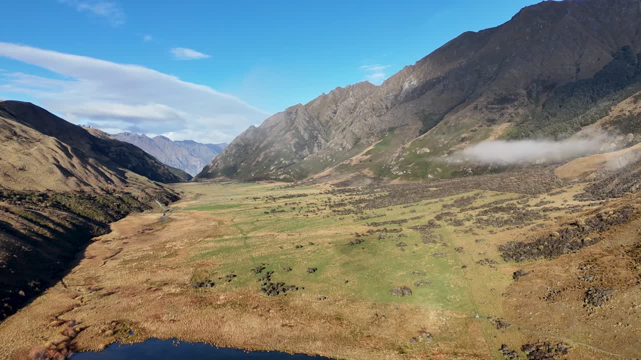Aerial footage captures Lake Moke's serene landscape in Queenstown, New Zealand, with sweeping mountain views and clear skies