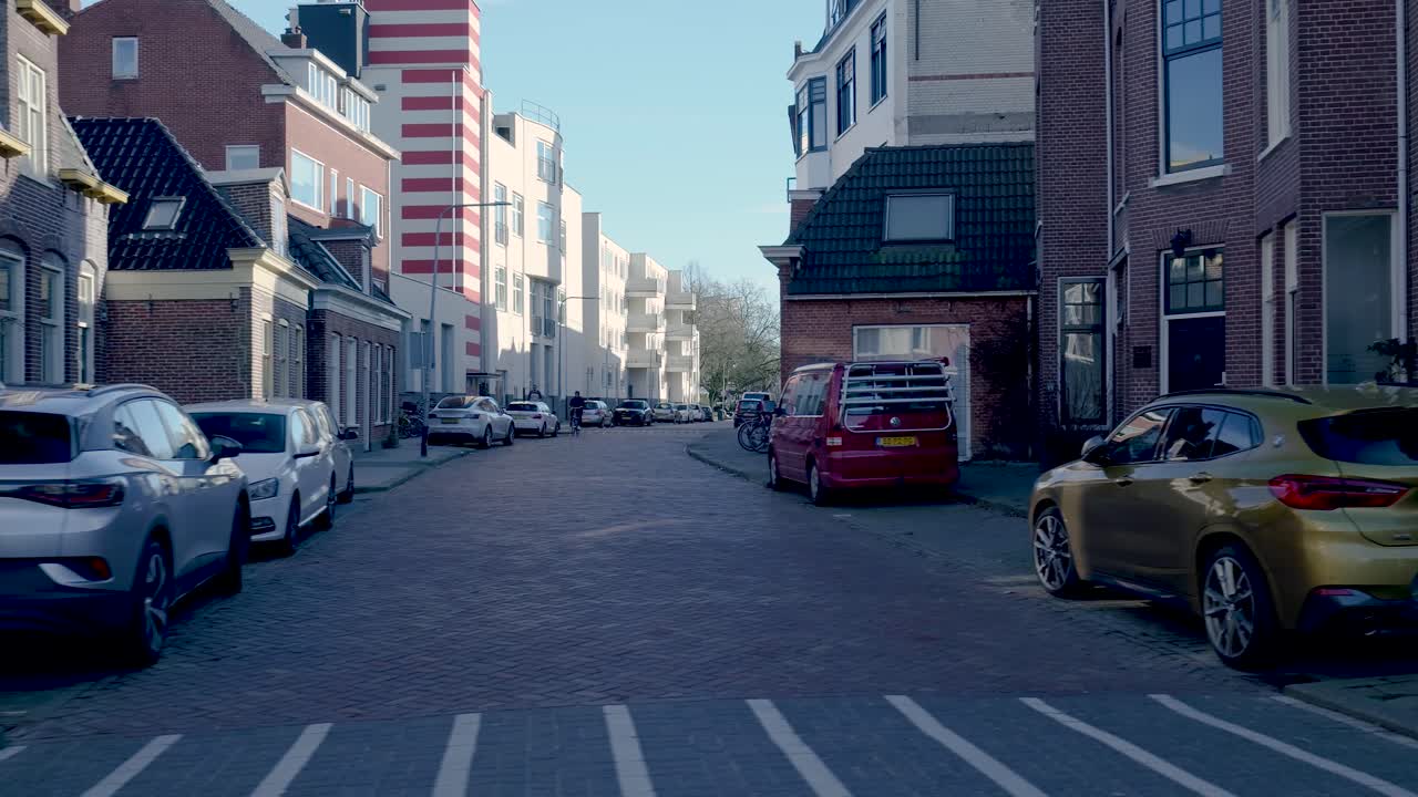 Caminhando por uma rua tranquila de uma cidade europeia com carros estacionados.