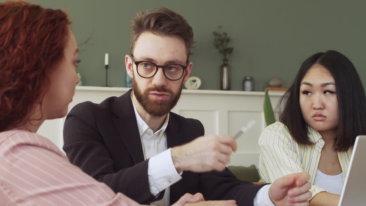 테이블에 앉아 작업에 대해 토론하는 세 명의 다민족 동료 그룹