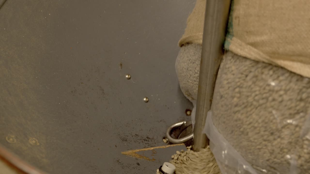 헤센 자루에서 산업용 로스터로 기울어지는 원시 흰색 커피 원두