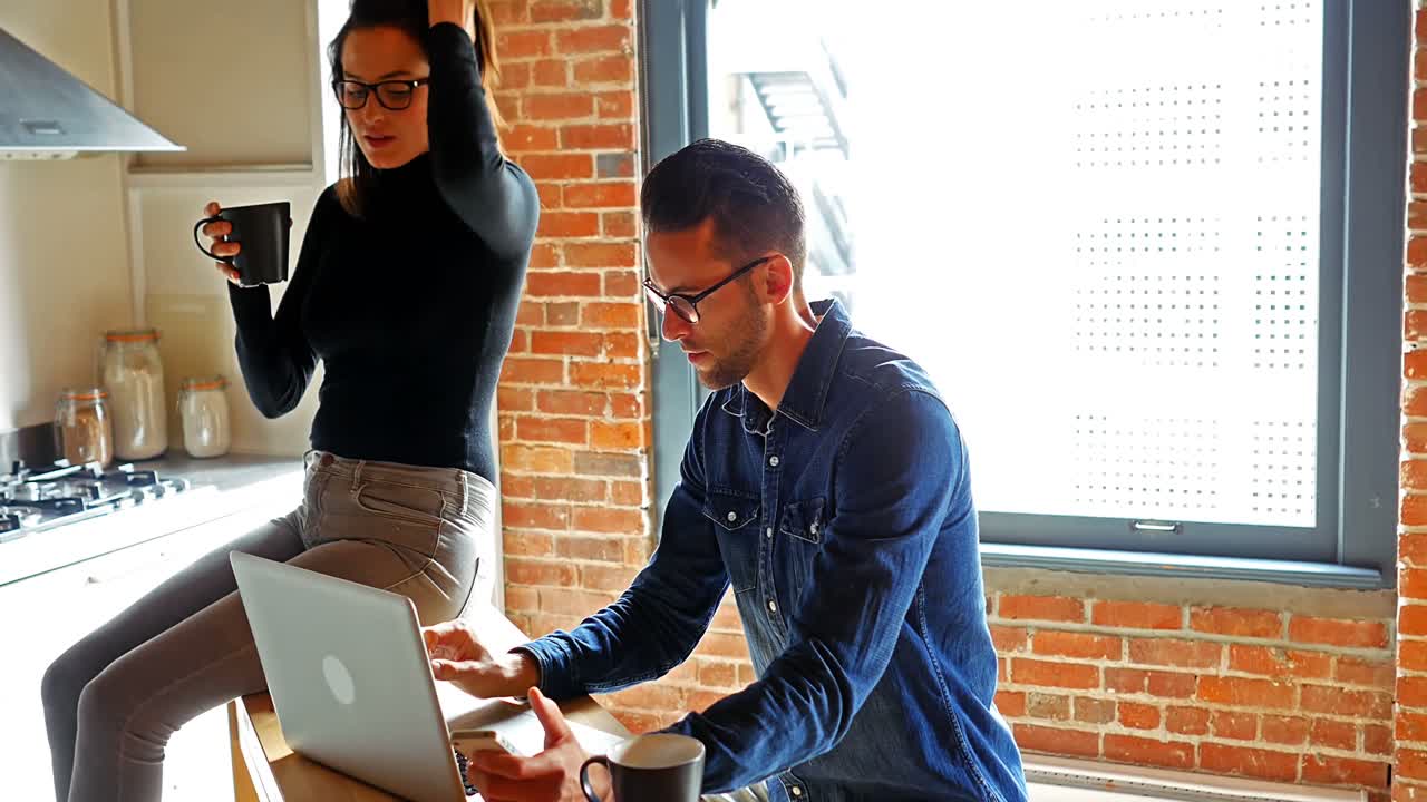 pareja usando una computadora portátil mientras toman café