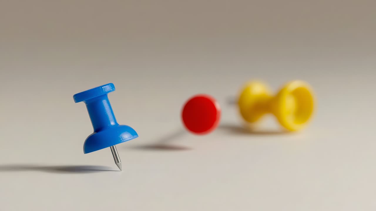 Closeup blue pushpin causing camera shifting focus and angle over beige table with red yellow pins
