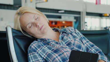 tired passenger sleeps in airport terminal while waiting for his flight