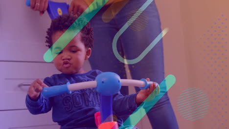 colorful shapes animation over child playing with toy bike indoors