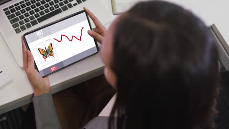 mujer de negocios biracial que usa una tableta para videollamadas con procesamiento de datos