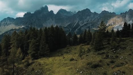 Un-Disparo-De-Un-Dron-Corona-Una-Colina-Boscosa-Para-Revelar-La-Majestuosa-Cordillera-De-Los-Alpes-En-Austria