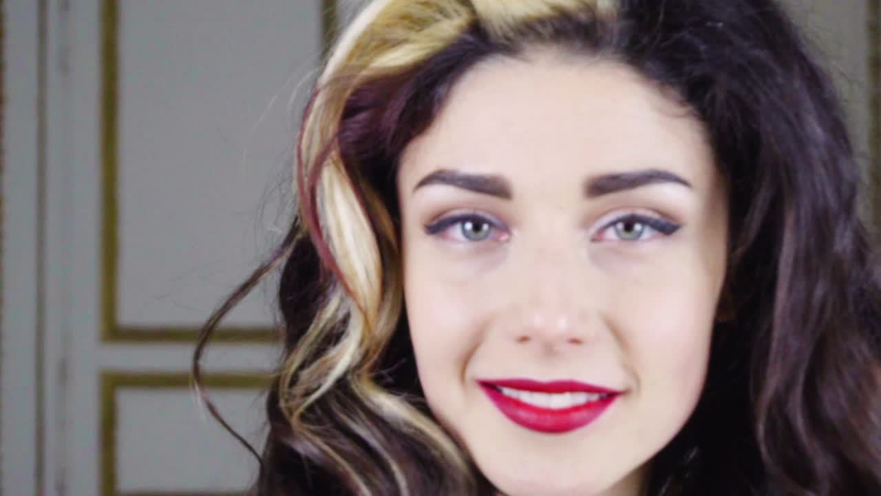 joven mujer morena con labios rojos mira a la cámara