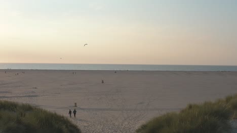 cinematic drone - aerial shot of the green and sandy nature beach with tourists and people with buggykiting at zeeland at the north sea, netherlands, 30p