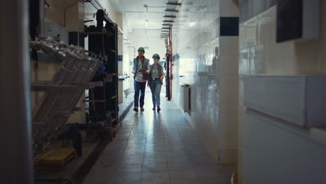 factory engineers walking production facility. supervisors discuss milking plans