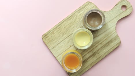 caramel, chocolate and mango pudding in a glass jar on pink background ,