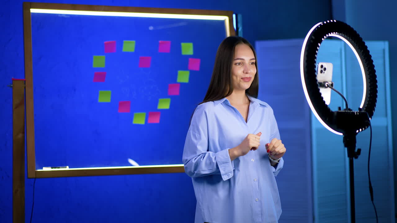 Beautiful positive Caucasian lady filming a blog. Girl talks to camera with the ring light. Blogger filming video.