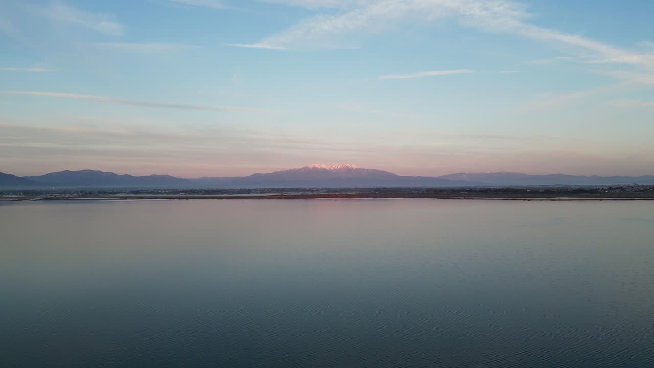 Aerial: Forward drone flight during sunrise along a coastline with mountain backdrop